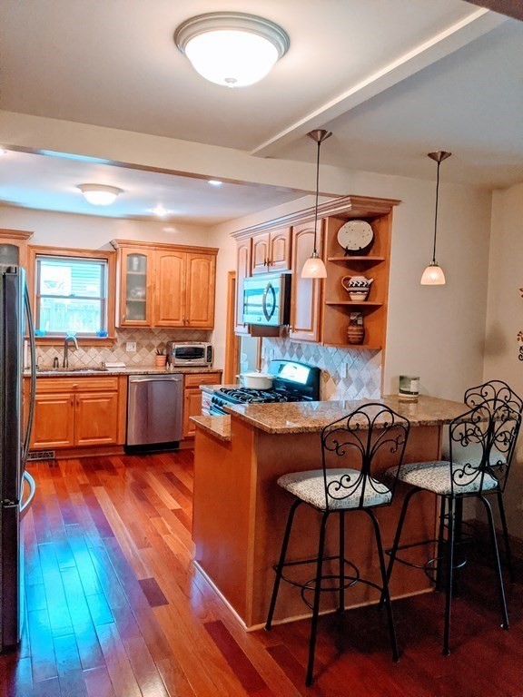 9 Byron Street Wakefield, MA 01880 - Photo 7 of 42 a open kitchen with stainless steel appliances granite countertop a stove top oven a sink dishwasher a dining table and chairs with wooden floor