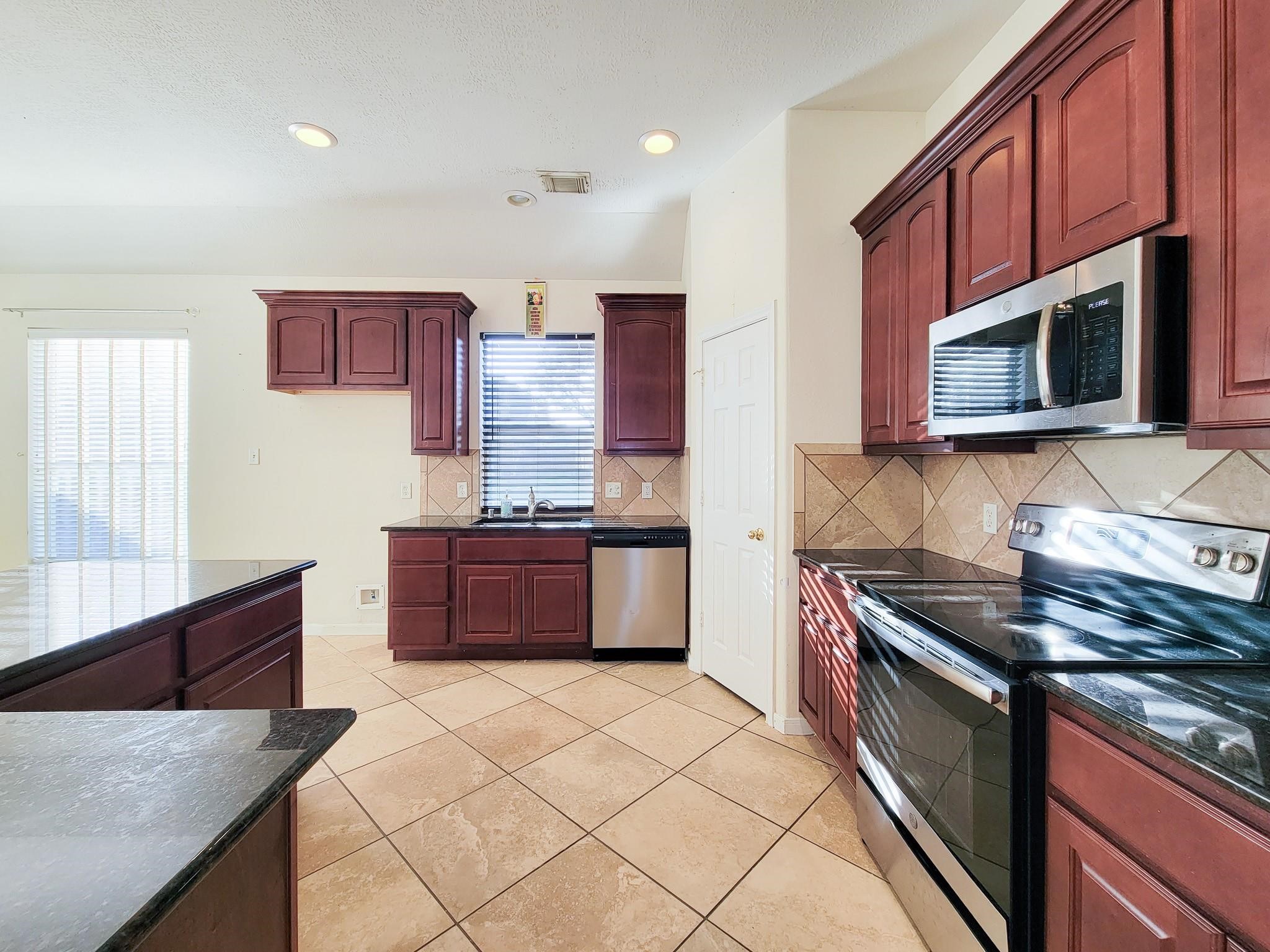 13935 Charterhouse Way Sugar Land, TX 77498 - Photo 12 of 36 a kitchen with stainless steel appliances granite countertop a stove a sink and a microwave