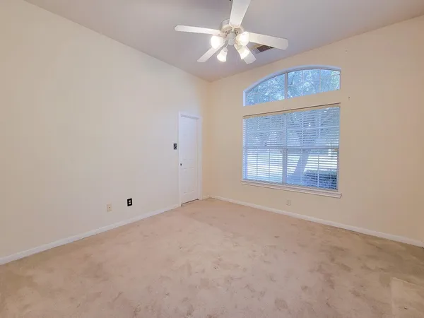 an empty room with a window and a fan