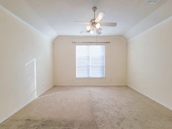an empty room with a chandelier fan and windows