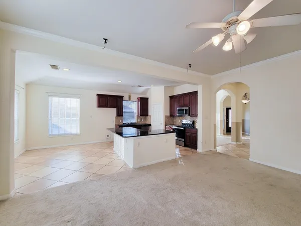 a view of a living room a kitchen and a chandelier fan