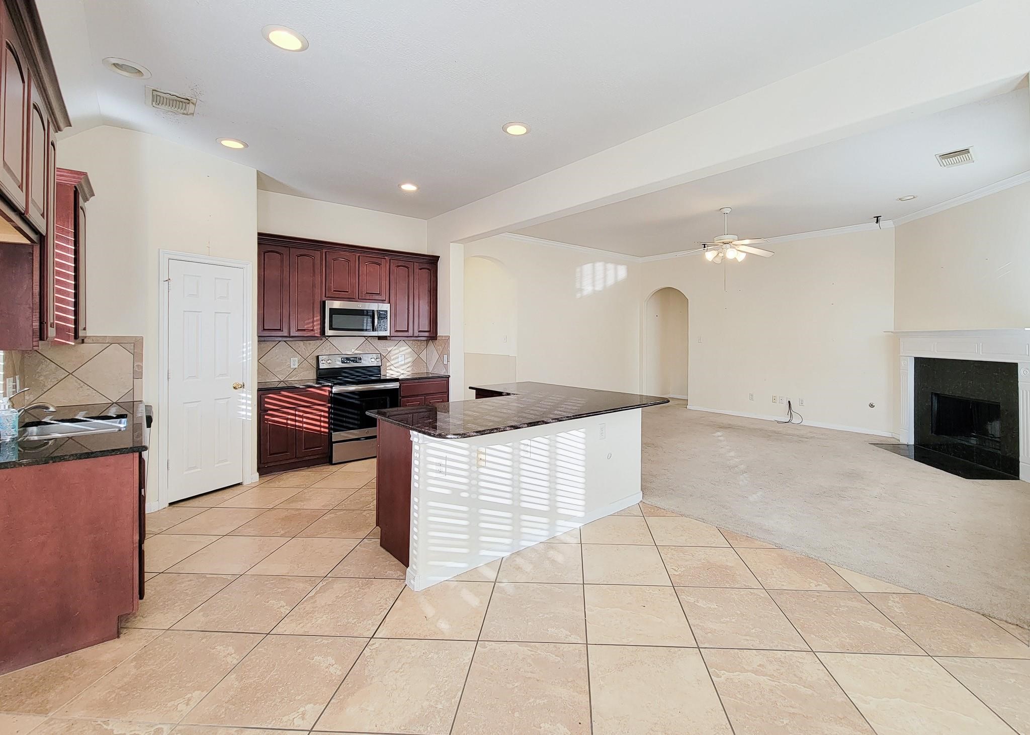 13935 Charterhouse Way Sugar Land, TX 77498 - Photo 9 of 36 a kitchen with stainless steel appliances kitchen island granite countertop a stove and a sink