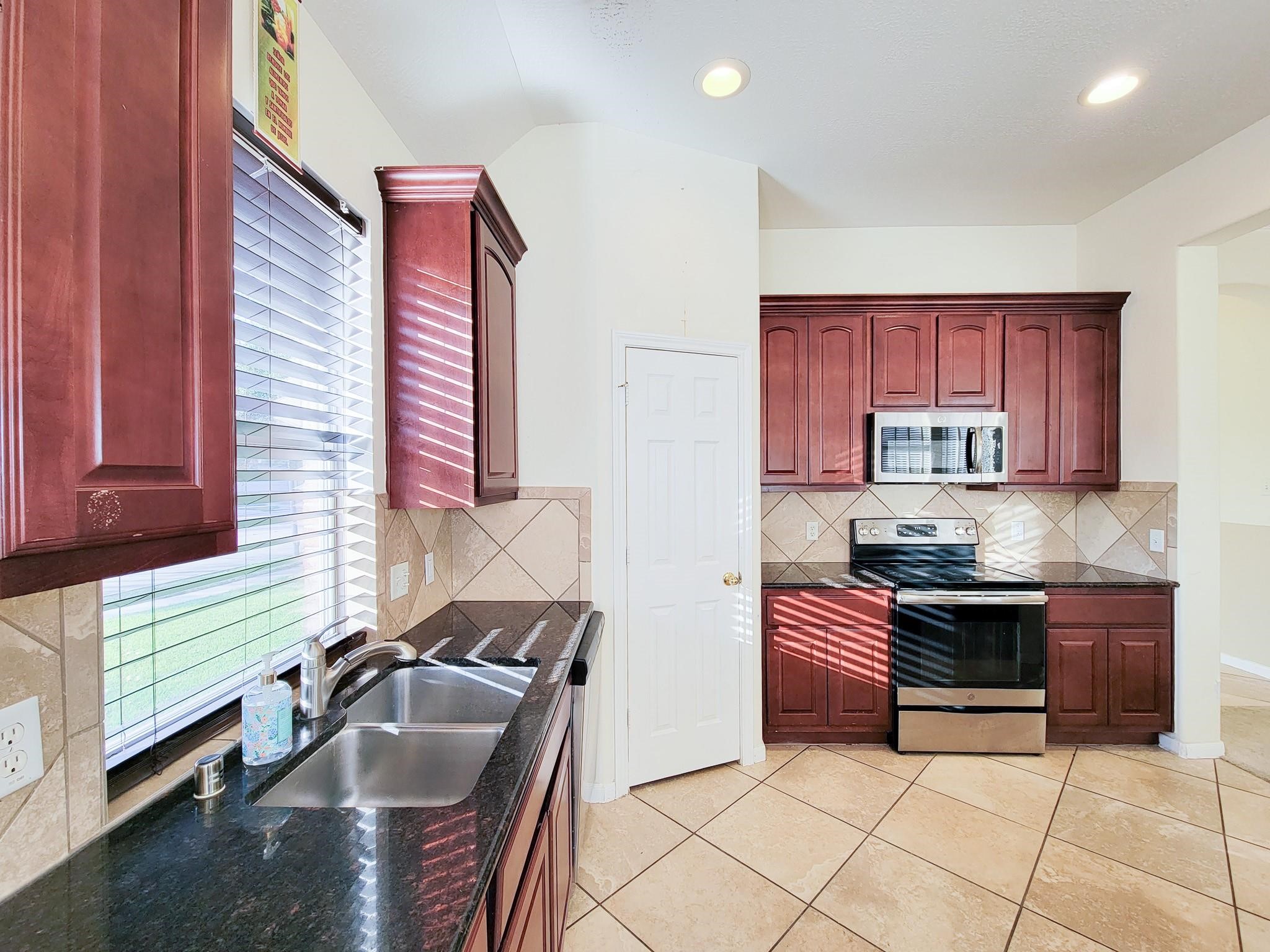 13935 Charterhouse Way Sugar Land, TX 77498 - Photo 10 of 36 a kitchen with granite countertop a stove sink and cabinets