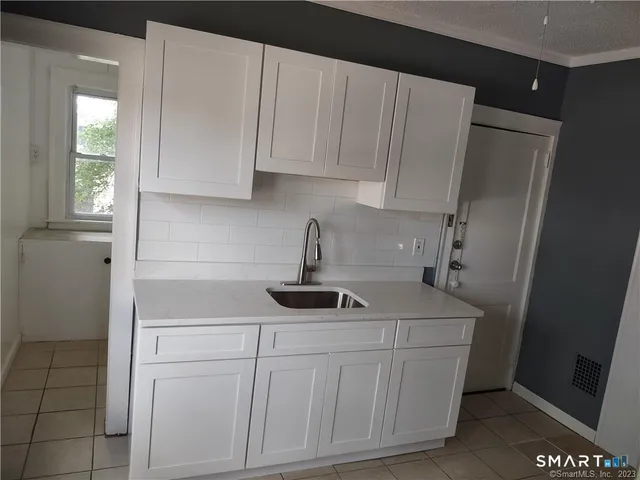 a kitchen with white cabinets and sink