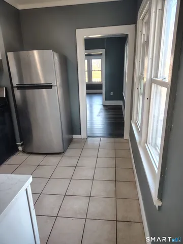 a view of a refrigerator in kitchen and an empty room with a fireplace