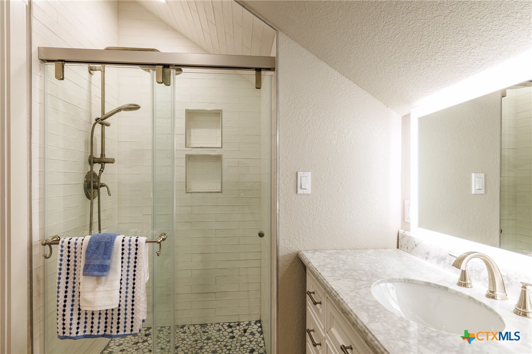 604 St Michael Street Gonzales, TX 78629 - Photo 26 of 37 a bathroom with a granite countertop sink a mirror and shower