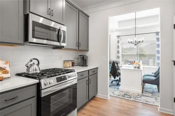 a kitchen with stainless steel appliances kitchen island granite countertop a sink a microwave a stove and white cabinets