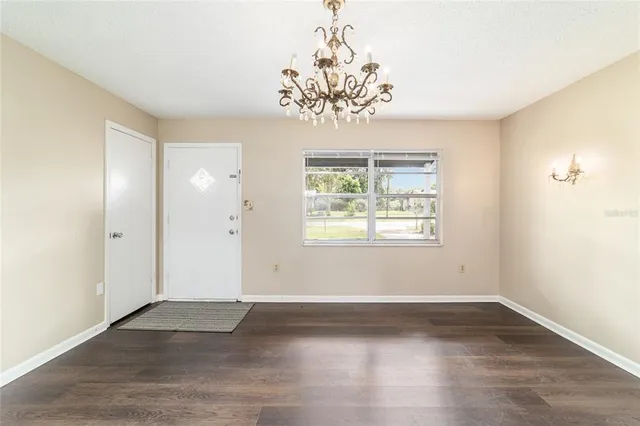 an empty room with wooden floor chandelier and windows