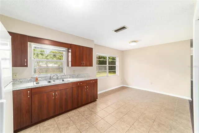 a large white kitchen with granite countertop a sink window and cabinets