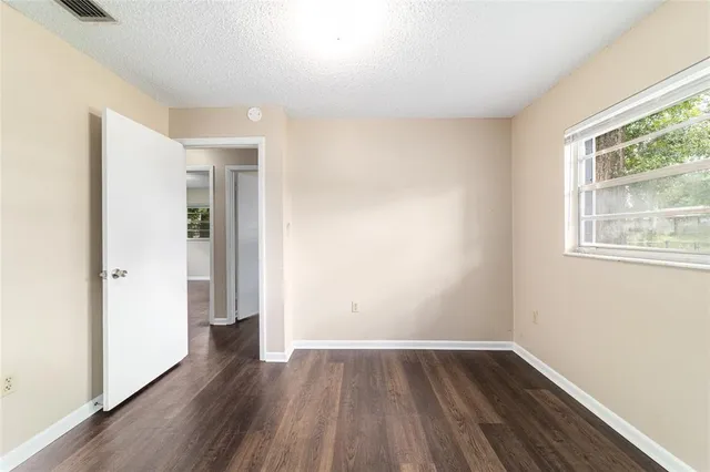 a view of an empty room with wooden floor and a window