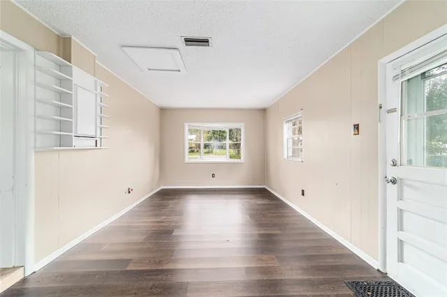 a view of an empty room with a window and wooden floor