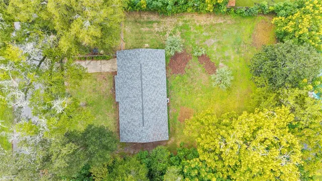 an aerial view of residential houses with outdoor space and trees all around