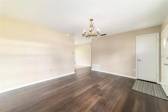 an empty room with wooden floor and chandelier fan