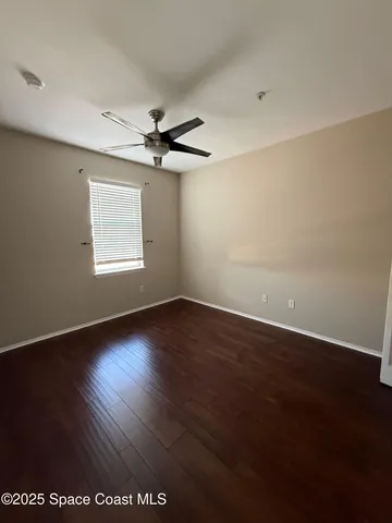 an empty room with wooden floor ceiling fan and windows