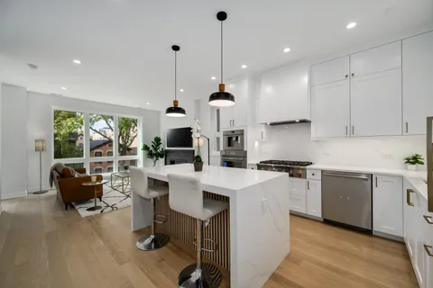 a large kitchen with stainless steel appliances kitchen island granite countertop a stove a sink dishwasher and a dining table with garden view