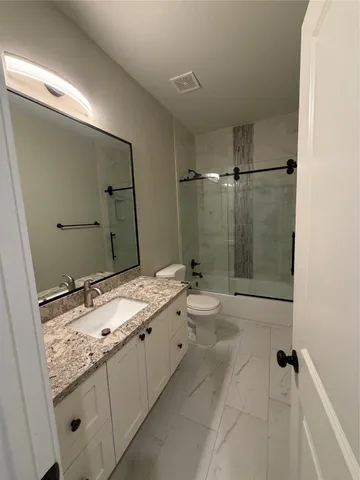 a bathroom with a granite countertop sink a toilet and shower