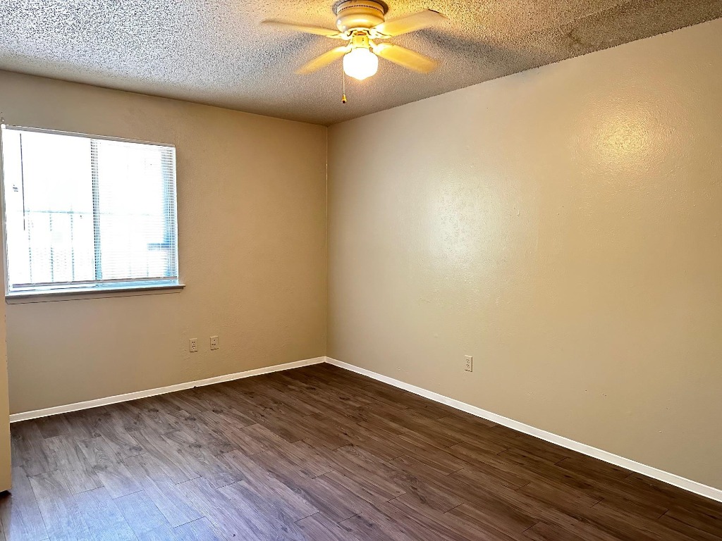 1102 Hickory Grove Drive, Unit B Austin, TX 78753 - Photo 7 of 14 an empty room with wooden floor and windows
