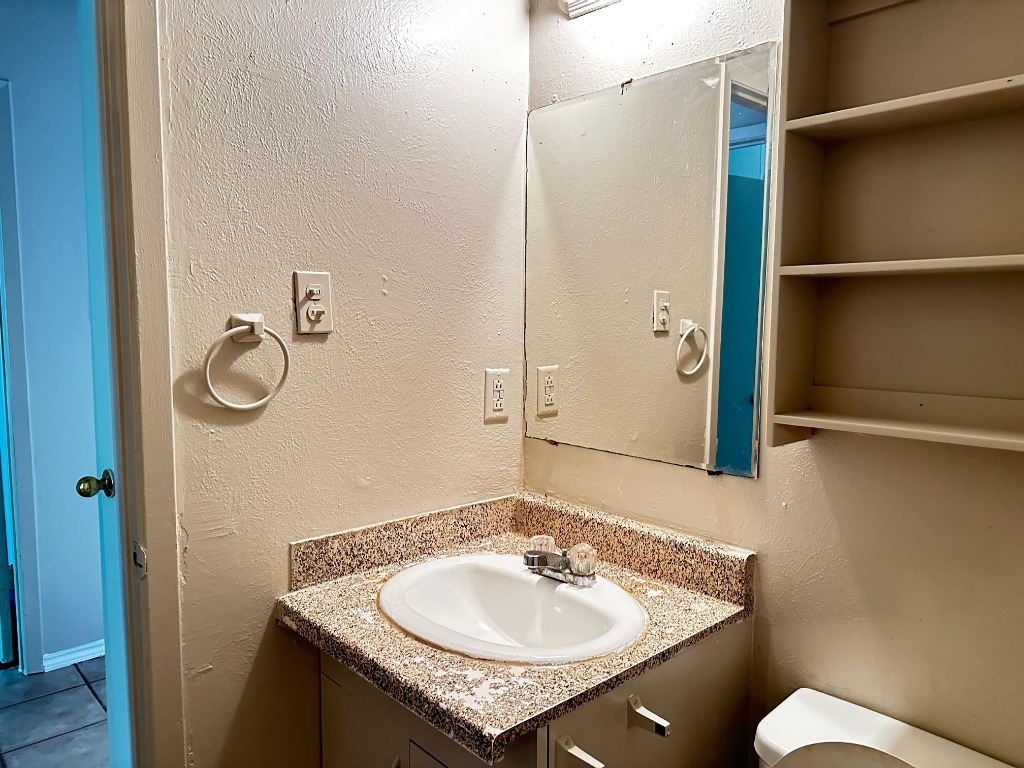 1102 Hickory Grove Drive, Unit B Austin, TX 78753 - Photo 10 of 14 a bathroom with a granite countertop sink and a mirror