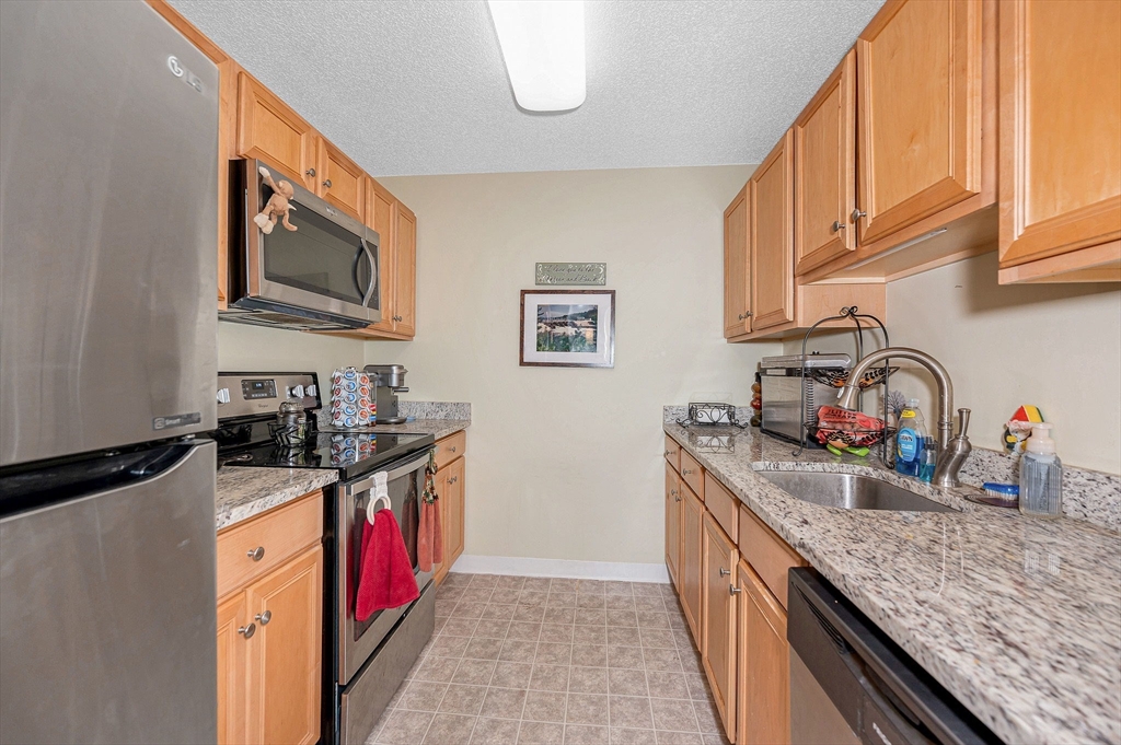 200 Market Street, Unit 3409 Lowell, MA 01852 - Photo 9 of 21 a kitchen with granite countertop a sink and a stove top oven