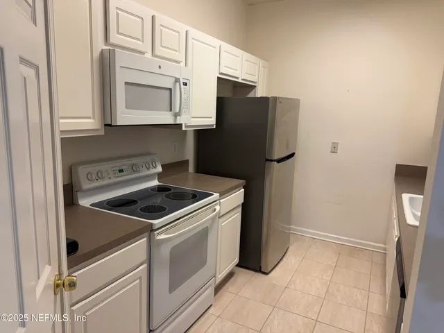 a kitchen with white cabinets and white appliances