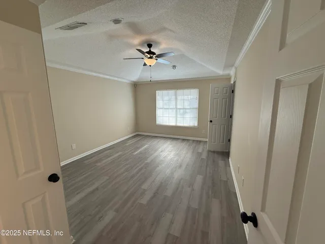 a view of an empty room with a window and wooden floor