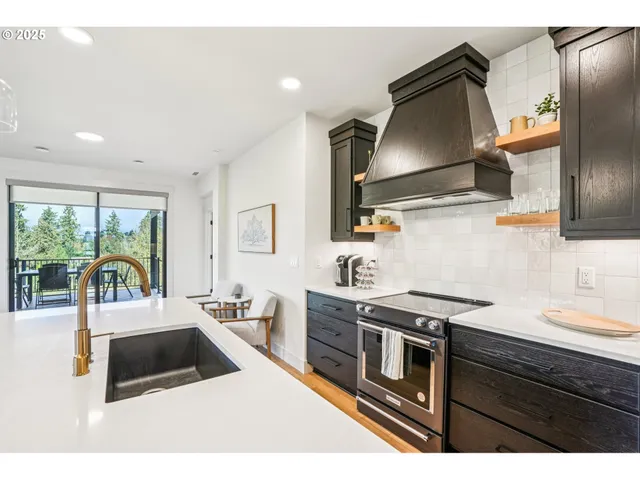 a kitchen with a stove a refrigerator a sink a counter space and wooden floor