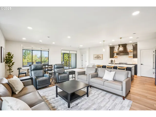 a living room with furniture kitchen view and a wooden floor