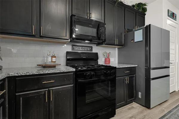 a kitchen with stainless steel appliances granite countertop a stove refrigerator and microwave with wooden cabinets
