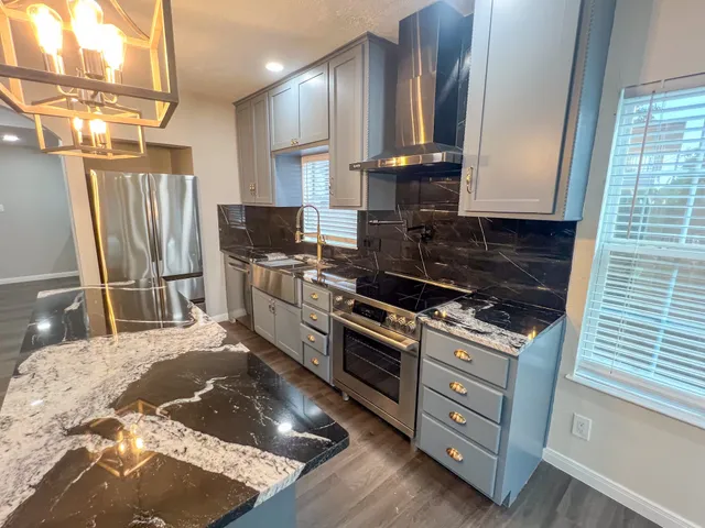 a kitchen with stainless steel appliances granite countertop a stove a sink and a refrigerator
