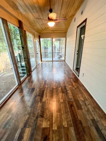 a view of empty room with wooden floor and fan