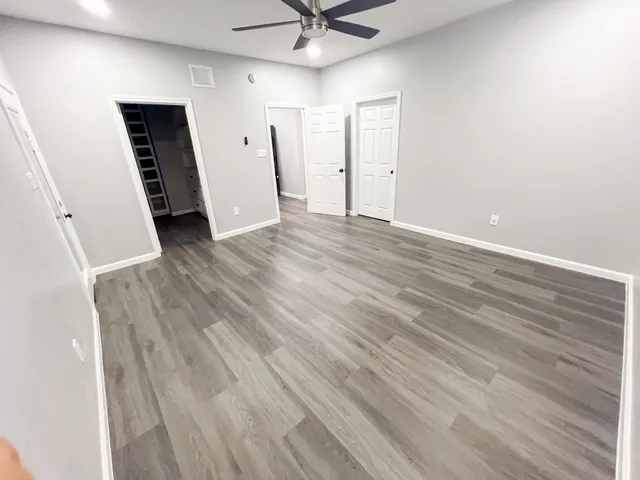 an empty room with wooden floor and a ceiling fan