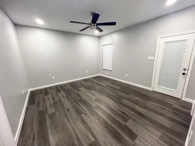 an empty room with wooden floor and windows