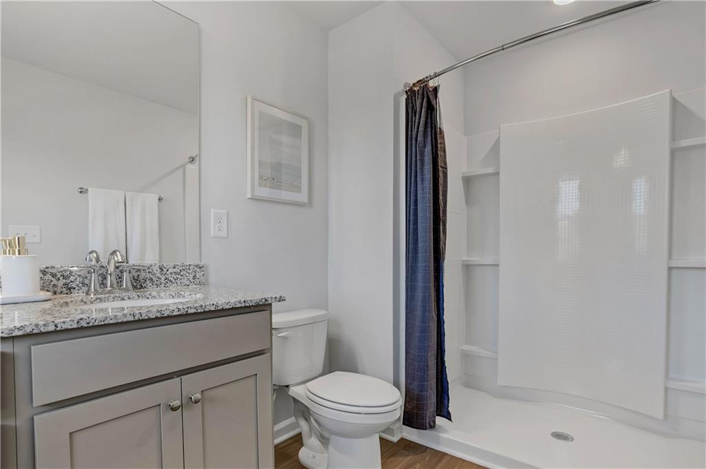1150 Hunter Trail, Unit ELDERFLOWER Acworth, GA 30102 - Photo 27 of 30 a bathroom with a granite countertop sink toilet and shower