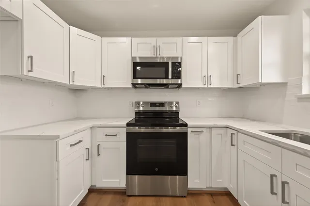 a kitchen with white cabinets and black appliances
