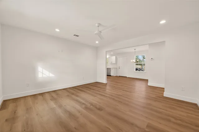 an empty room with wooden floor staircase and windows