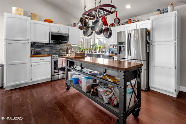 a kitchen with stainless steel appliances granite countertop a refrigerator a stove and a wooden floors