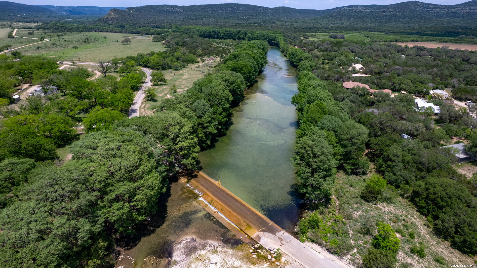 270 Robinson Road Concan, TX 78838 - Photo 2 of 50 an aerial view of green landscape with trees houses and mountain view