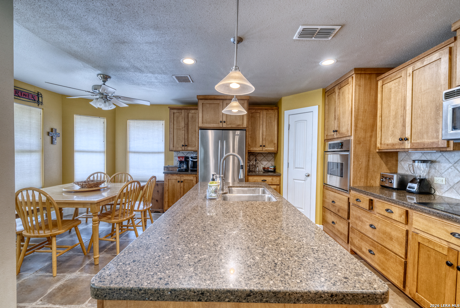 270 Robinson Road Concan, TX 78838 - Photo 21 of 50 a view of a kitchen with granite countertop a dining table chairs stainless steel appliances and cabinets