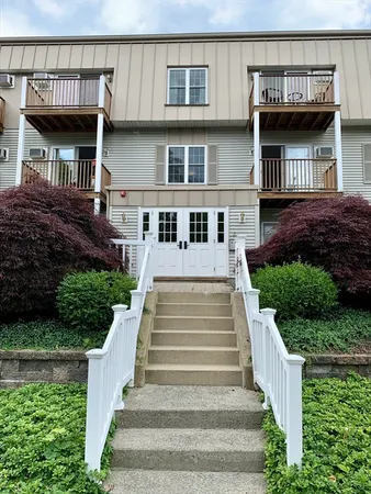a view of a house with large windows and a yard in front of main door