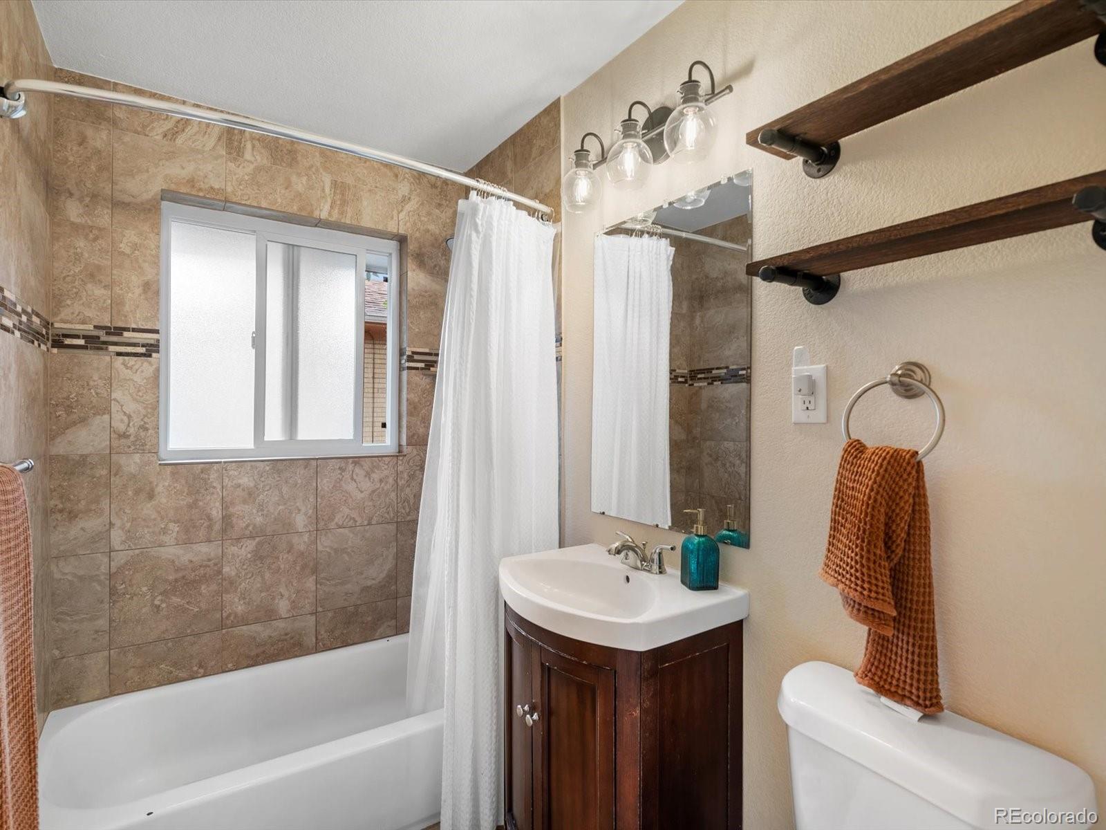 4963 North Harlan Street Wheat Ridge, CO 80033 - Photo 16 of 42 a bathroom with a sink and mirror with bathtub
