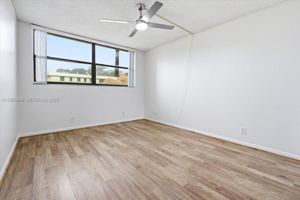 491 Racquet Club Road, Unit 107 Weston, FL 33326 - Photo 19 of 34 wooden floor in an empty room with a window