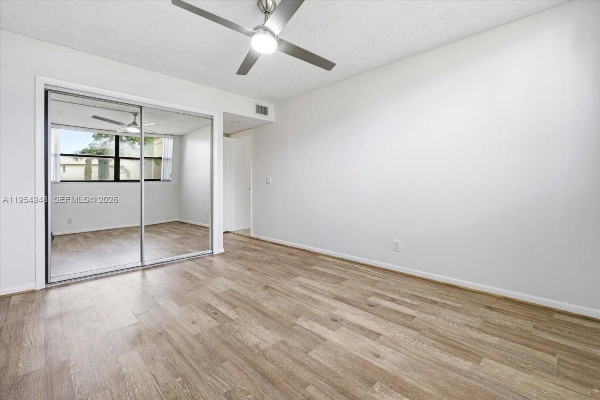 491 Racquet Club Road, Unit 107 Weston, FL 33326 - Photo 20 of 34 an empty room with wooden floor cabinet and windows