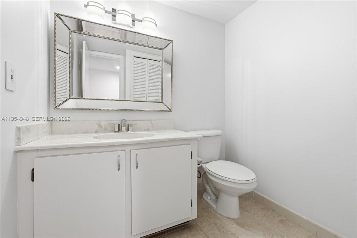 491 Racquet Club Road, Unit 107 Weston, FL 33326 - Photo 9 of 34 a bathroom with a toilet sink vanity and mirror