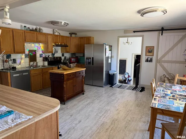 a kitchen with stainless steel appliances kitchen island granite countertop a sink stove and refrigerator