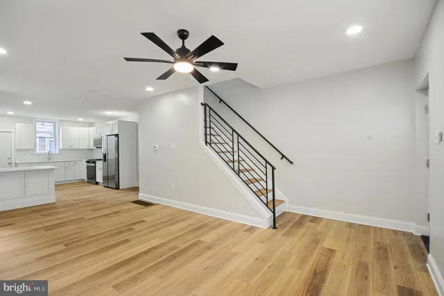 a view of an empty room with wooden floor and a ceiling fan