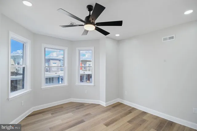 a view of an empty room with a window and wooden floor