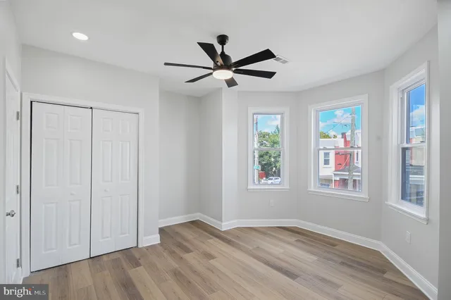 a view of empty room with wooden floor and fan