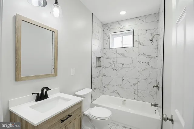a bathroom with a bathtub shower sink vanity and toilet