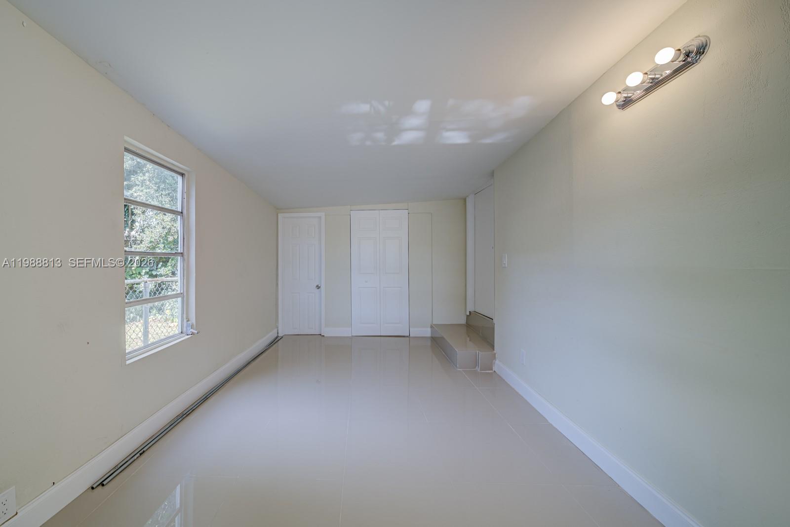 829 Northwest 56th Street Miami, FL 33127 - Photo 12 of 25 wooden floor in an empty room with a window