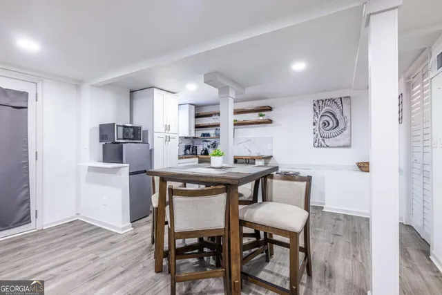 a kitchen with stainless steel appliances a dining table chairs and wooden floor